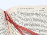 an open book with a red ribbon on top of it