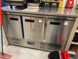 un comptoir en métal, avec une serpillière et un seau posés par terre