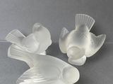une paire de figurines de poissons en verre transparent posées sur un support gris