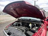 une voiture rouge dont le capot est ouvert, garée dans la rue