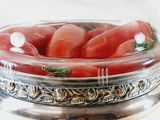 a glass bowl with tomatoes inside of it on a stand