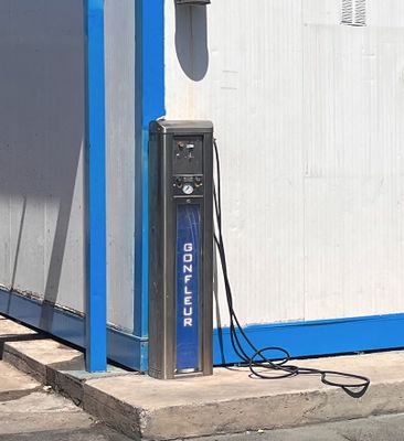 un bâtiment bleu et blanc équipé d'une borne de recharge électrique sur le trottoir