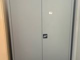 une armoire métallique placée dans un coin de la pièce, près d'une porte