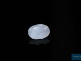 une pierre de jade blanche posée sur une surface noire