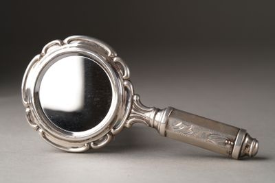 a silver magnifying glass with a handle on a table