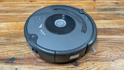 un gros plan d'un aspirateur robot posé sur une table en bois