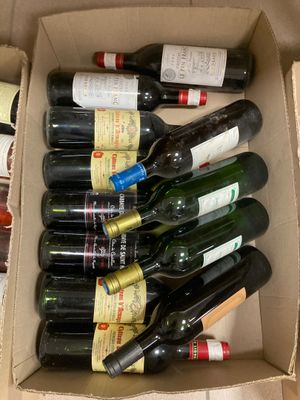 plusieurs bouteilles de vin dans un carton posé sur le sol