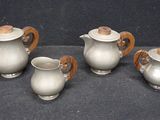 three silver teapots with wooden handles sitting on a black surface