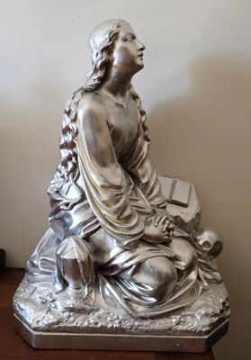 une statue en argent représentant une femme assise sur une table