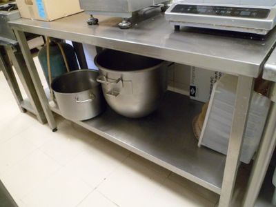 une étagère métallique sur laquelle sont posés une casserole et une poêle, dans une cuisine