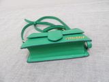 green purse on a bed with a white sheet in the background