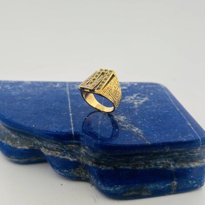 a close up of a gold ring on top of a blue stone