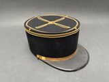 chapeau noir orné d'une bordure dorée et d'un motif représentant deux os croisés sur le dessus