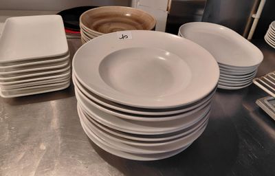 a lot of white plates and bowls on the counter