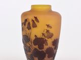 un vase jaune orné de fleurs noires sur un fond blanc