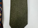 two ties on a white surface one has a green tie and the other has a brown tie
