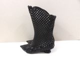 black boot shaped vase on white table with white background
