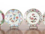 four plates with different designs on them sitting on a wooden table