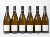 six bouteilles de vin sont alignées sur une surface blanche