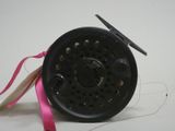 a black fly reel with a pink ribbon on a white surface