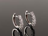 a pair of diamond hoop earrings on a reflective surface