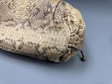 snake skin purse on a table with a blue background