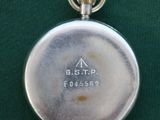 an image of a silver pocket watch sitting on a green surface