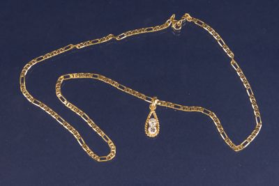 un gros plan d'un collier en or orné d'un pendentif en forme de larme