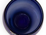 blue glass bowl on a white surface with a black rim