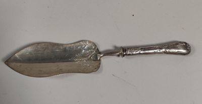 une vieille cuillère en argent avec un manche en métal posée sur une surface blanche