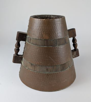 a brown vase with a wooden handle on a white surface