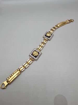 une photo d'un bracelet en or et en argent posé sur une surface blanche