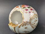 un petit vase blanc orné d'un motif doré