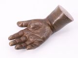 bronze sculpture of a hand holding a cup on a white surface