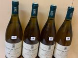 four bottles of wine are lined up on a wooden stand