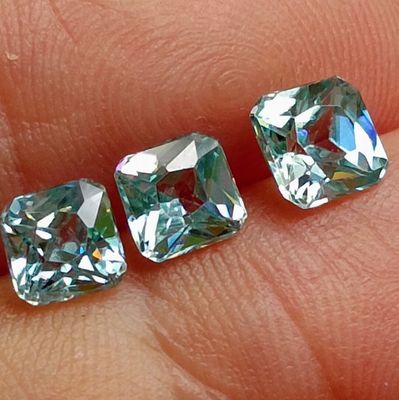 three square cut aquamarinee diamonds on a person ' s finger
