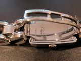 a close up of a silver watch on a black surface