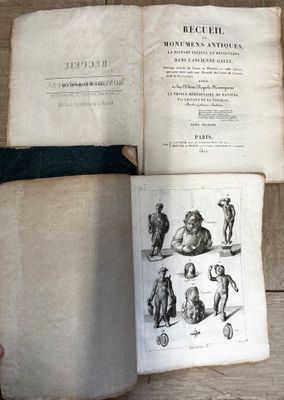 Quelqu'un tient un livre ouvert posé sur un plancher en bois sur lequel figurent des dessins.