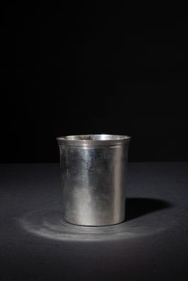 a metal cup sitting on a table with a black background