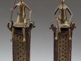 pair of bronze figurines of a woman and a man sitting on top of a pedestal