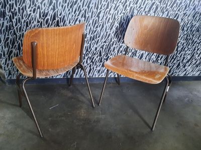 deux chaises en bois placées l'une à côté de l'autre devant un mur