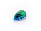 a green and blue oplite stone on a white surface