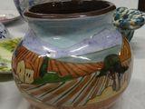 a vase with a painting on it sitting on a table