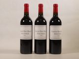 trois bouteilles de vin rouge sont alignées sur une surface blanche