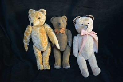three teddy bears sitting next to each other on a black background
