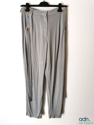 un pantalon gris suspendu à un cintre devant un mur blanc