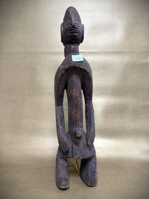 an old wooden statue of a man with a blue tag on it ' s neck