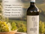 une bouteille de vin posée sur une table, à côté d'un bol de raisins