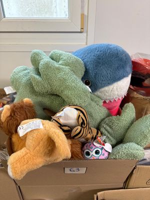 de nombreuses peluches dans une boîte en carton posée par terre