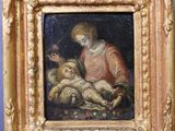 une image représentant un tableau d'une femme tenant un bébé dans ses bras, dans un cadre doré